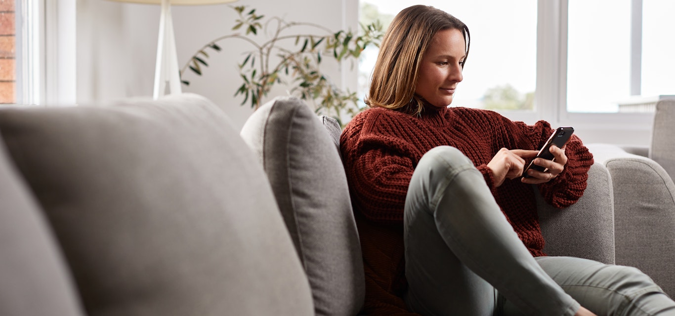 woman at home on couch looking at phone