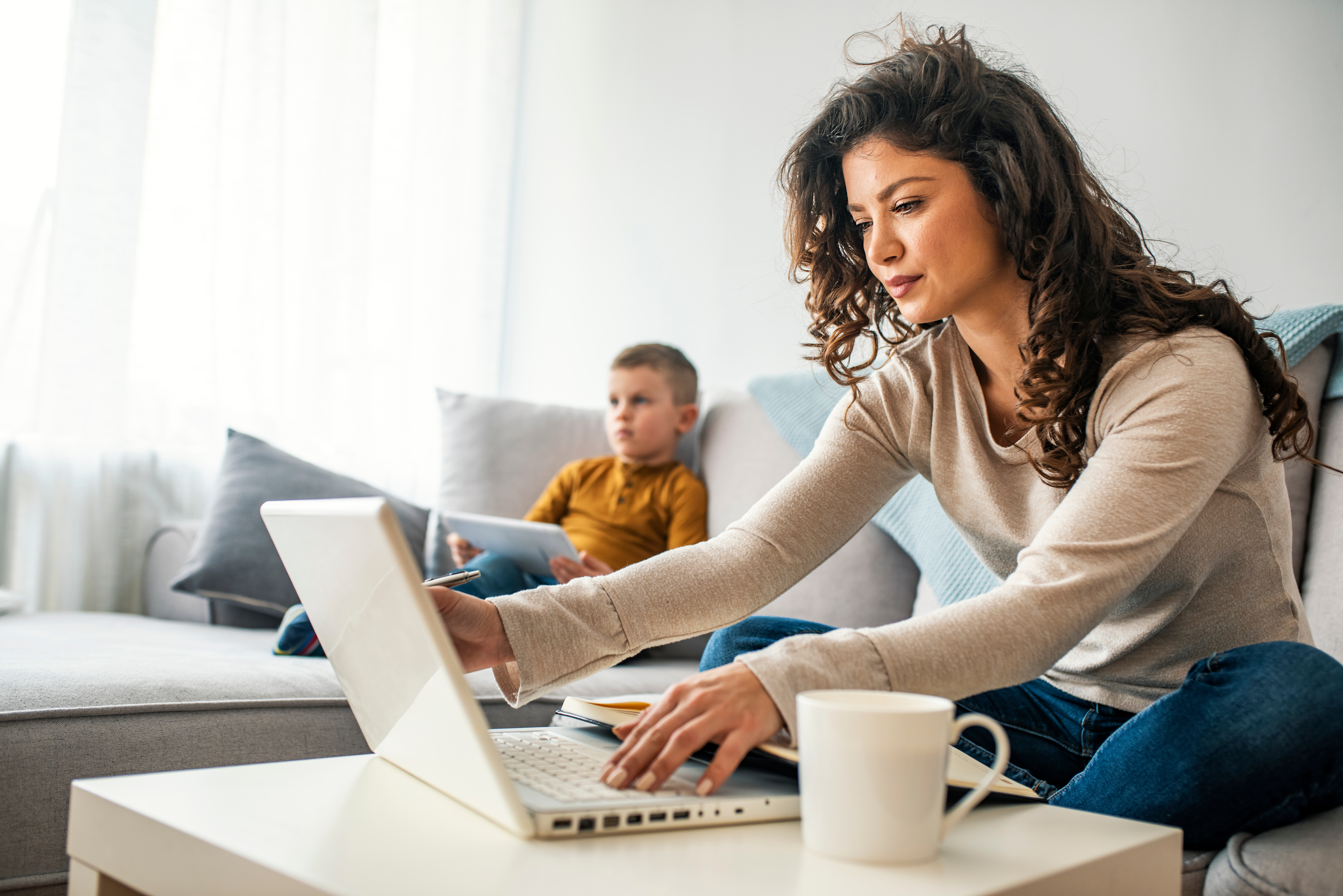 Woman and child on couch looking at electronic devices