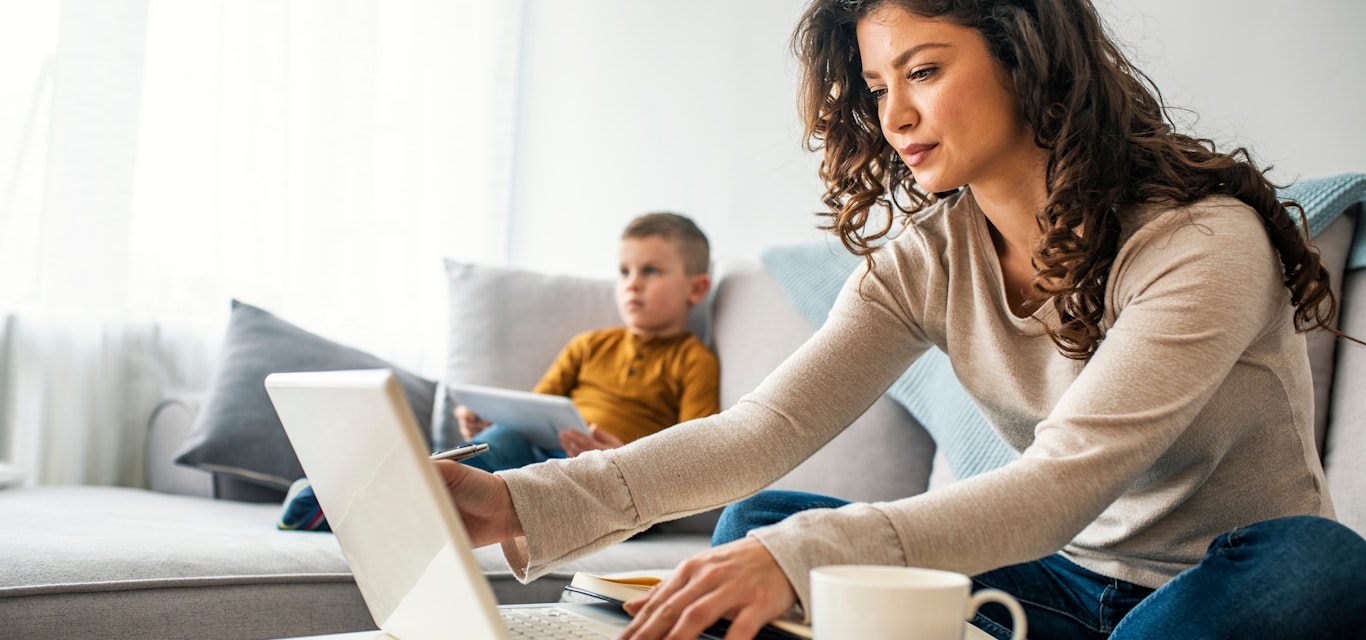 Woman and child on couch looking at electronic devices