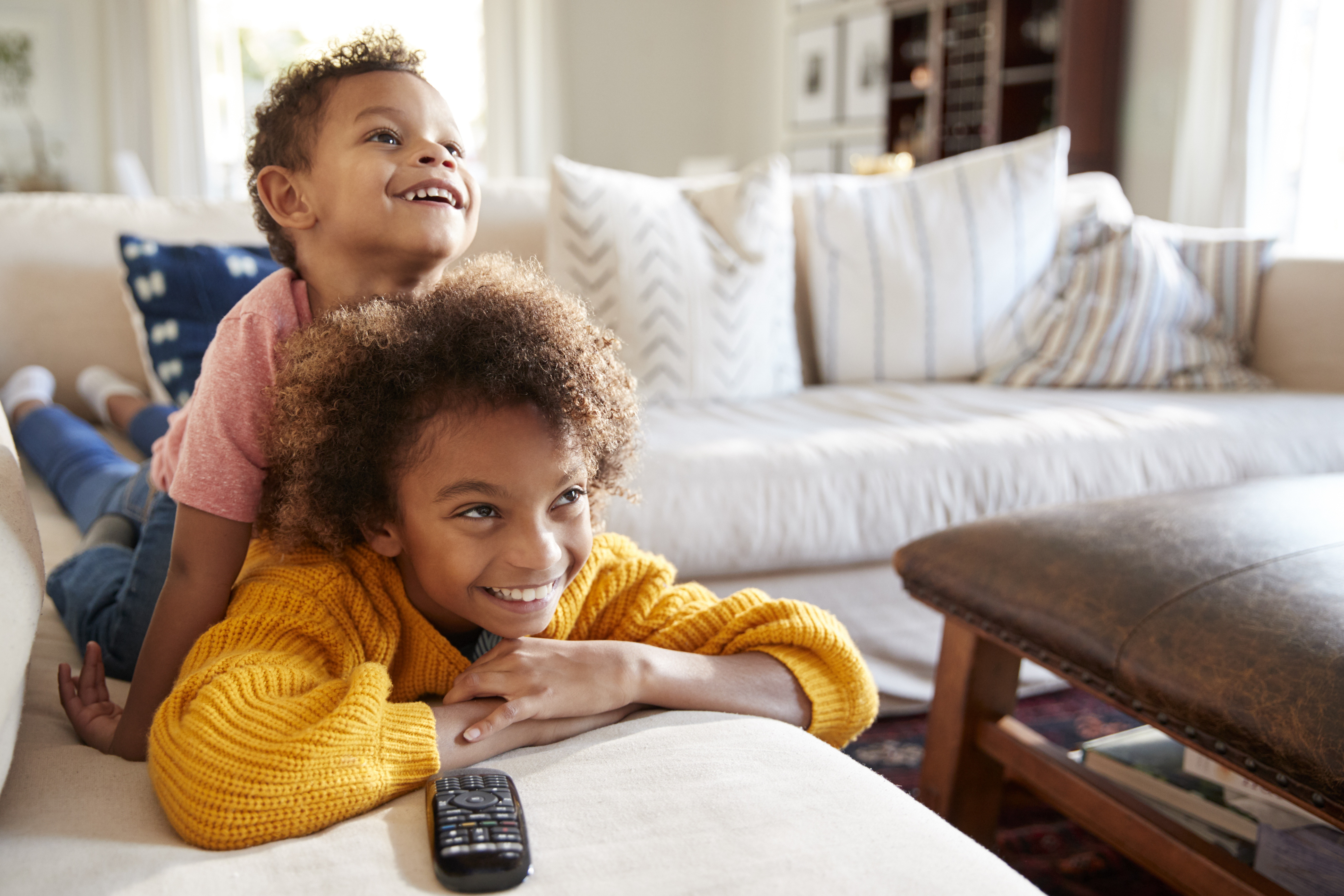 Kids laying on the couch watching TV.