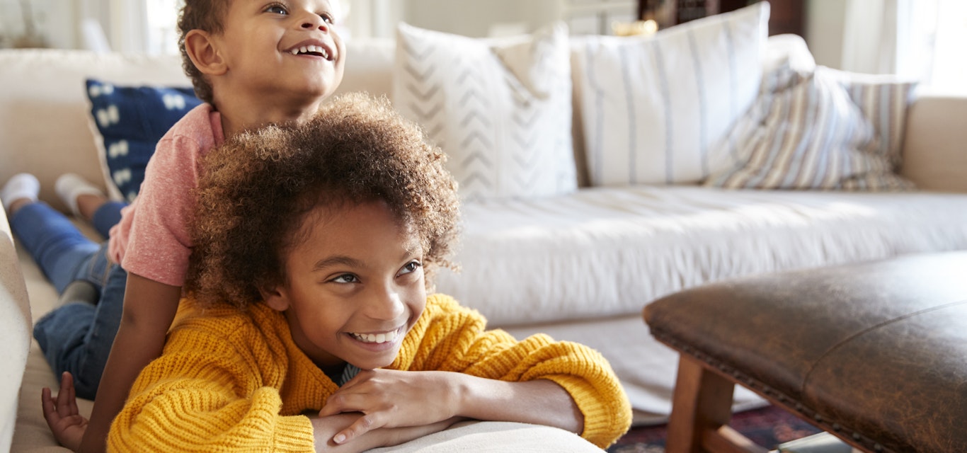 Kids laying on the couch watching TV.