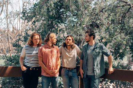 four men standing in front of trees