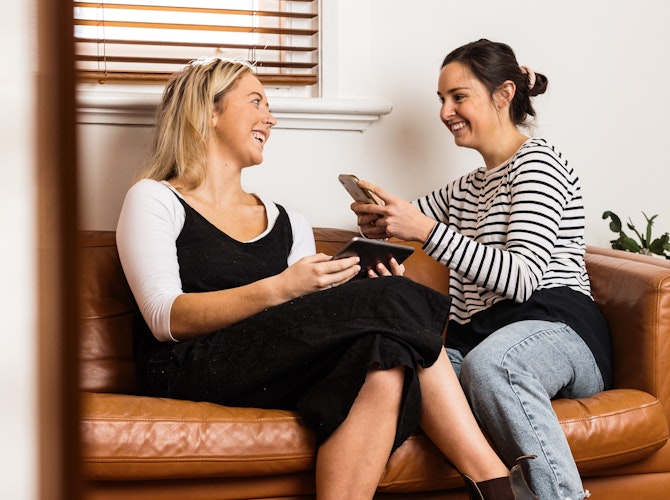 Women chatting on couch with mobile devices