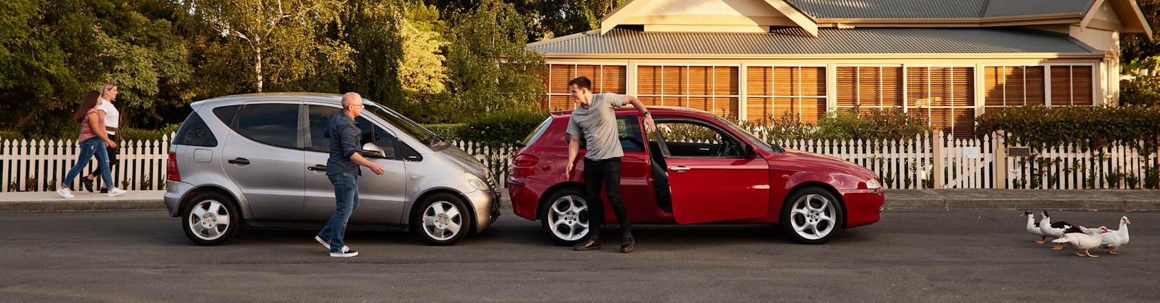 Two men talking beside cars after an accident.