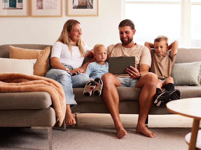 Family sitting on couch looking at a laptop.
