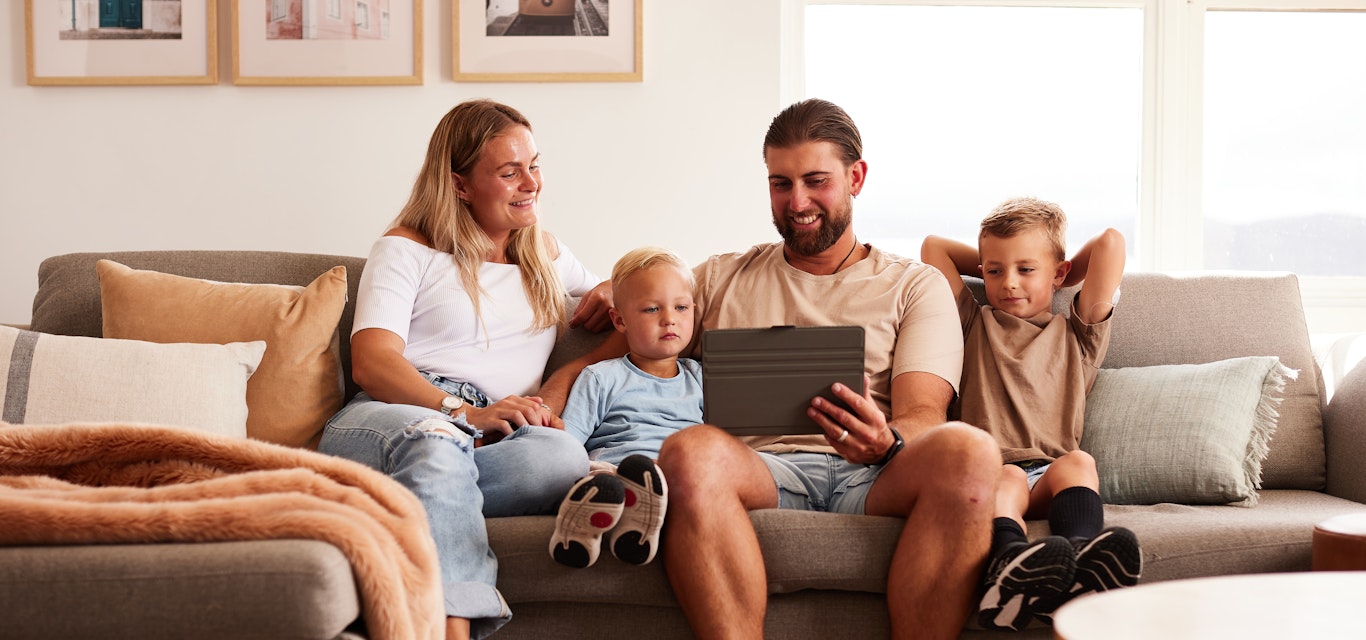 Family sitting on couch looking at a laptop.