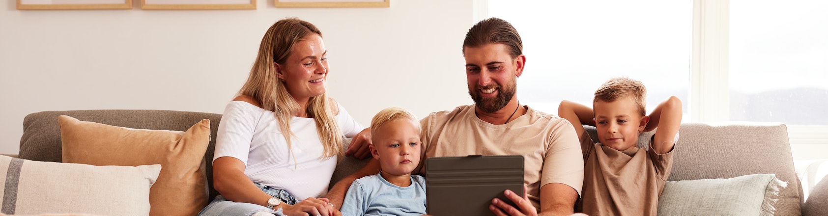 Family sitting on couch looking at a laptop.