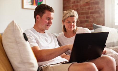 Couple on couch looking at laptop screen