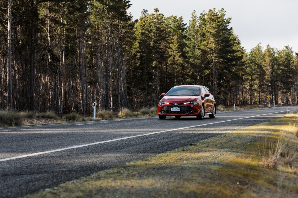 Red car driving on road near Seven Mile Beach.