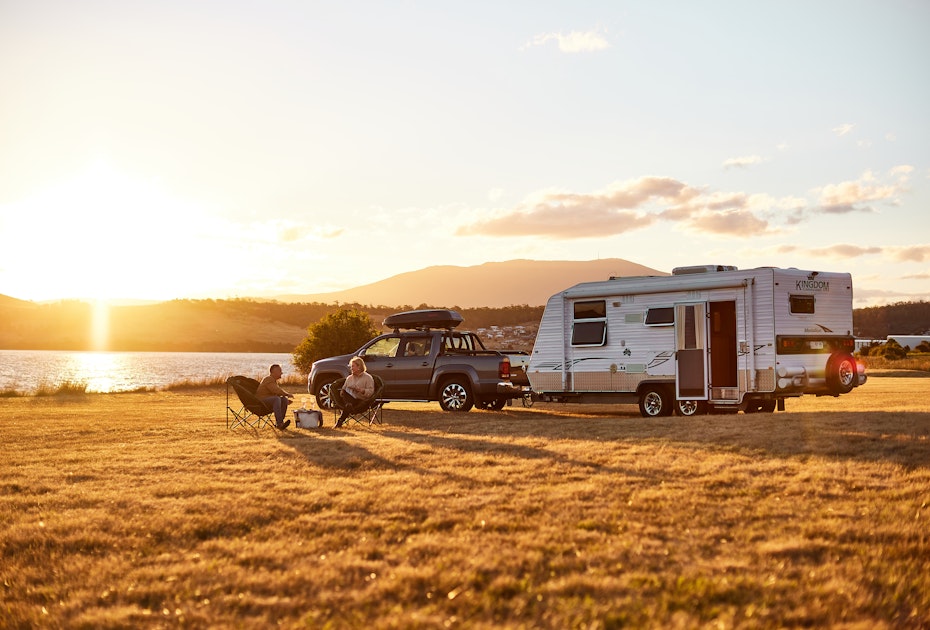 Couple relaxing outside caravan at sunset.