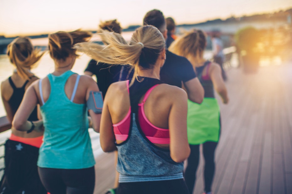 backs of people running on boardwalk