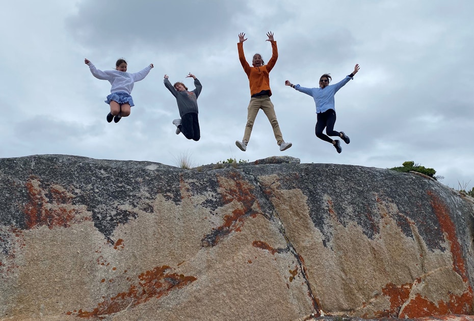 family jumping on top of rock