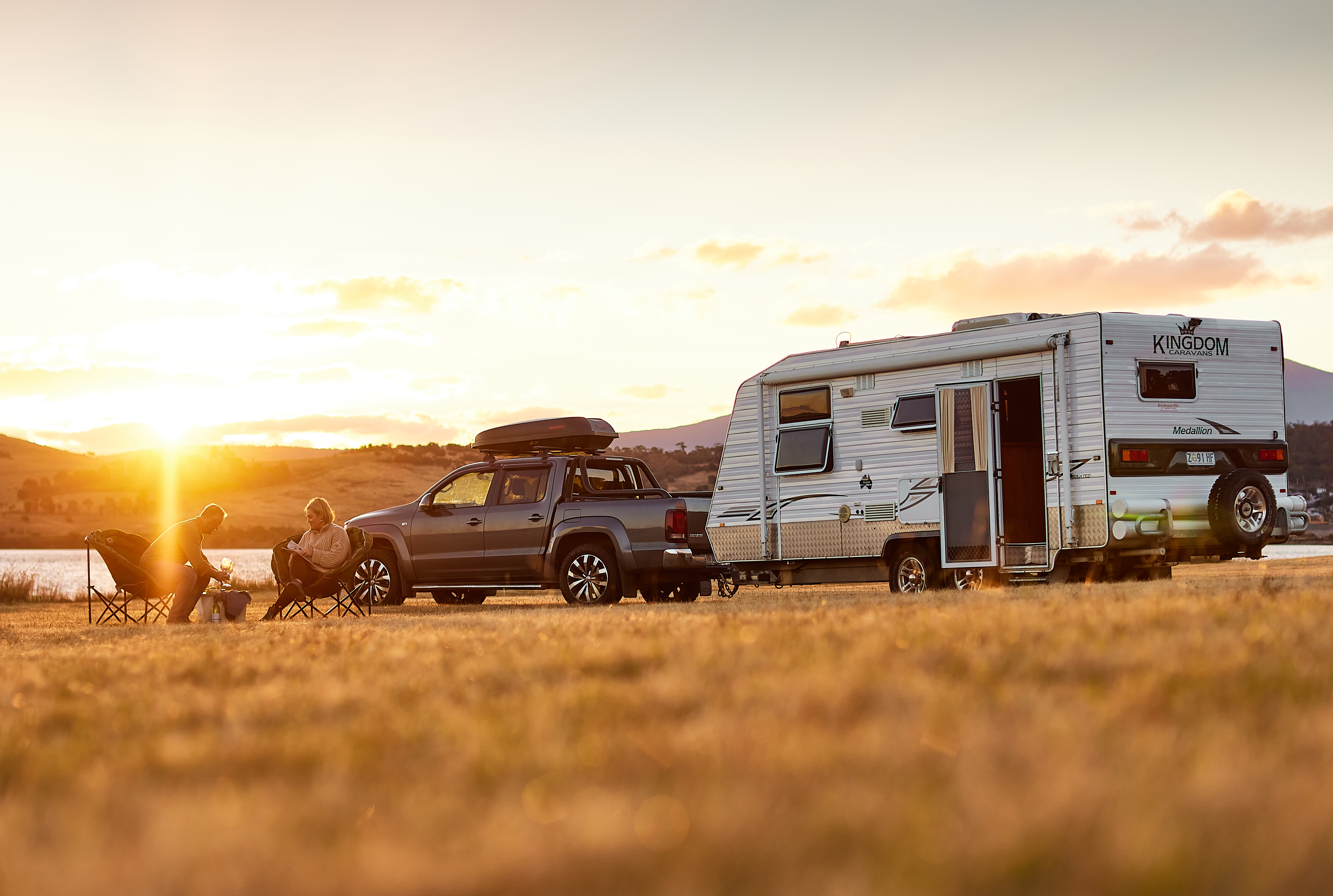 couple sitting near their caravan at sunset