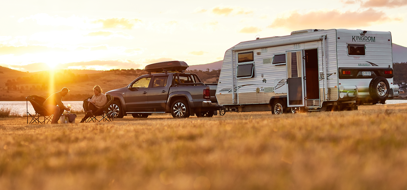 couple sitting near their caravan at sunset