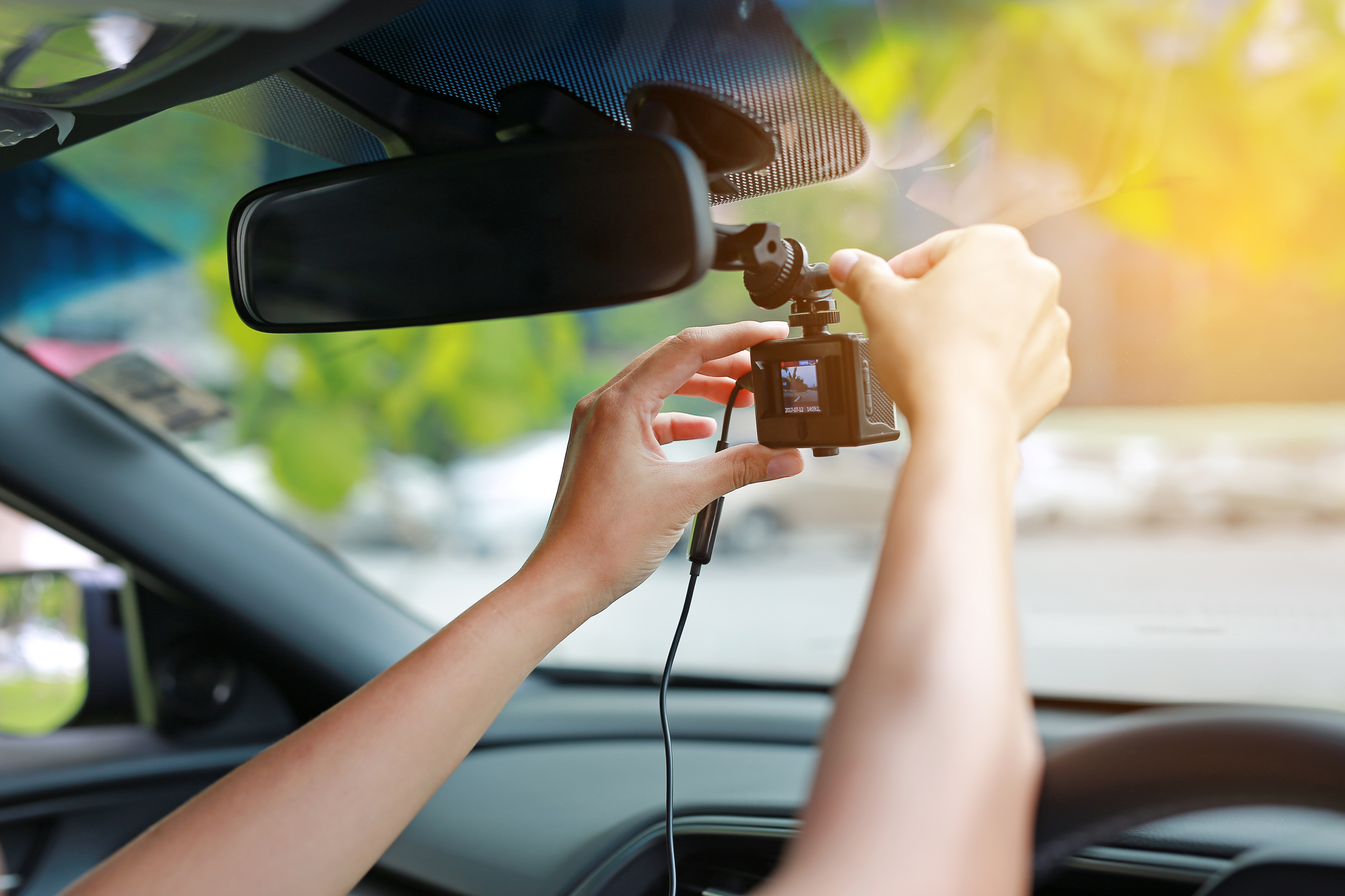 Person attaching a dash cam to their windscreen