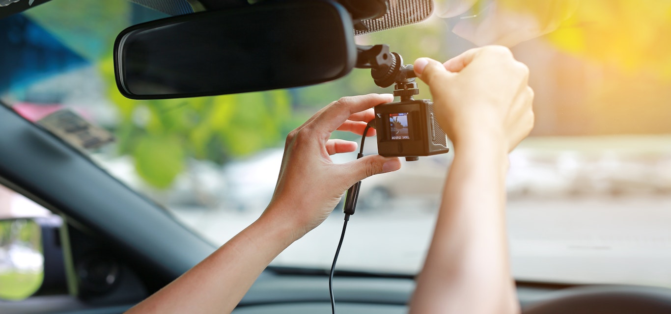 Person attaching a dash cam to their windscreen