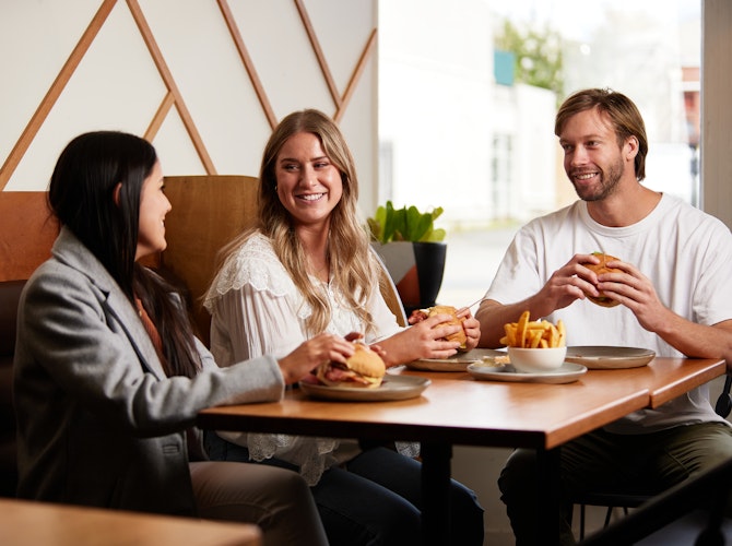 Trio of young people enjoying burgers at diner