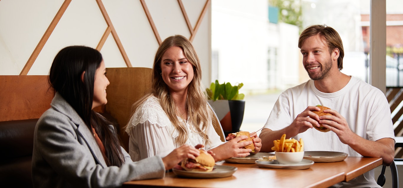 Trio of young people enjoying burgers at diner