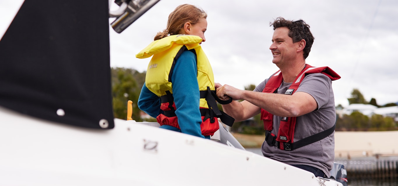 man helping child to put on a life jacket 