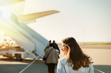 Woman walking across tarmac to board a plane