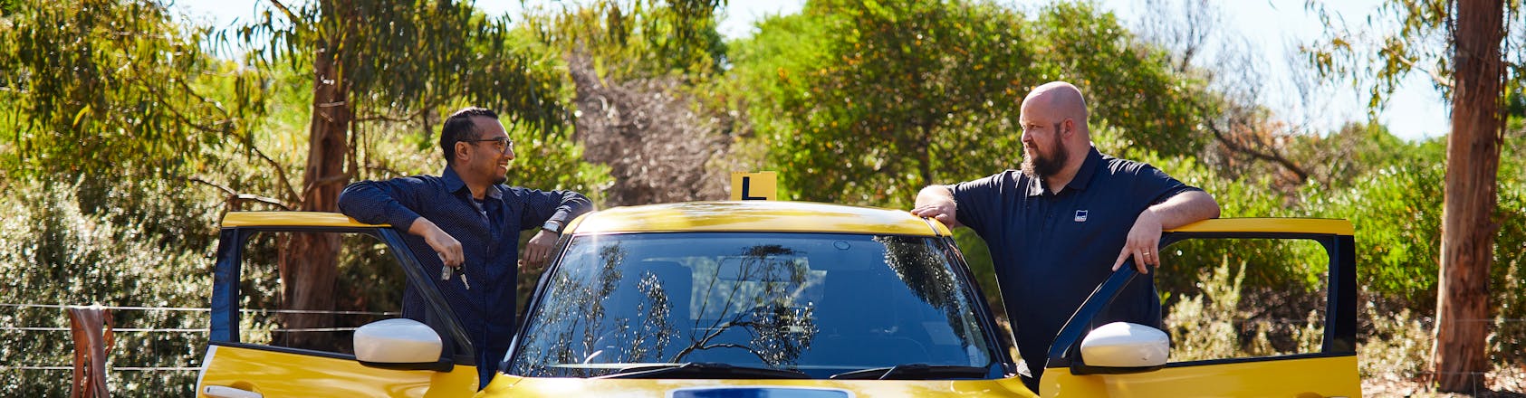 Learner driver and instructor standing near car