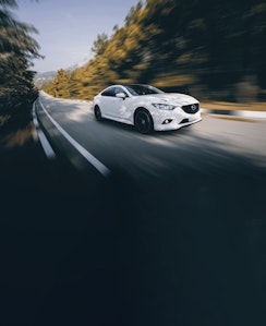 white mazda on road blurred