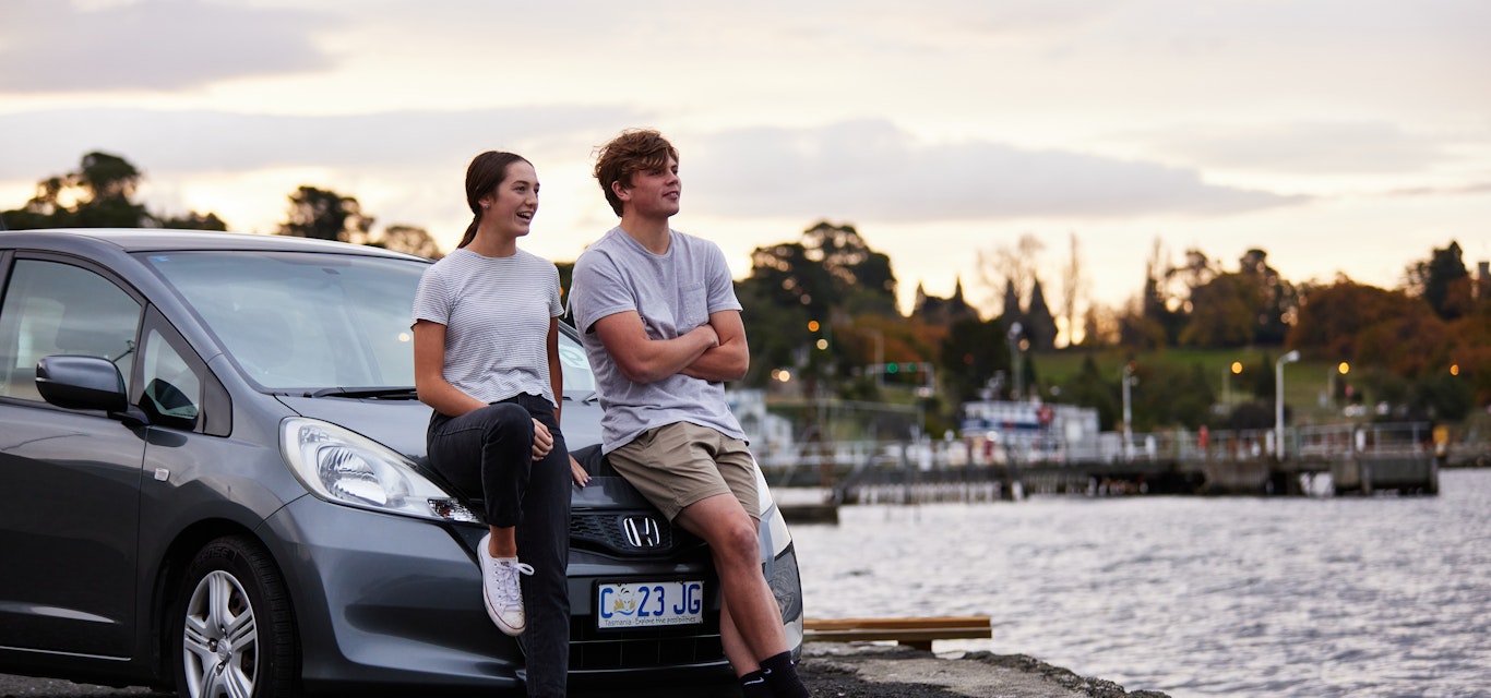 Couple sitting on car in parking lot