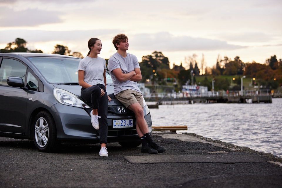 Couple sitting on car in parking lot