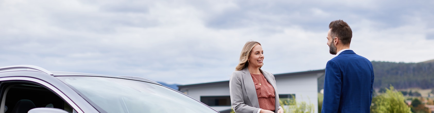 Couple standing around family car chatting.