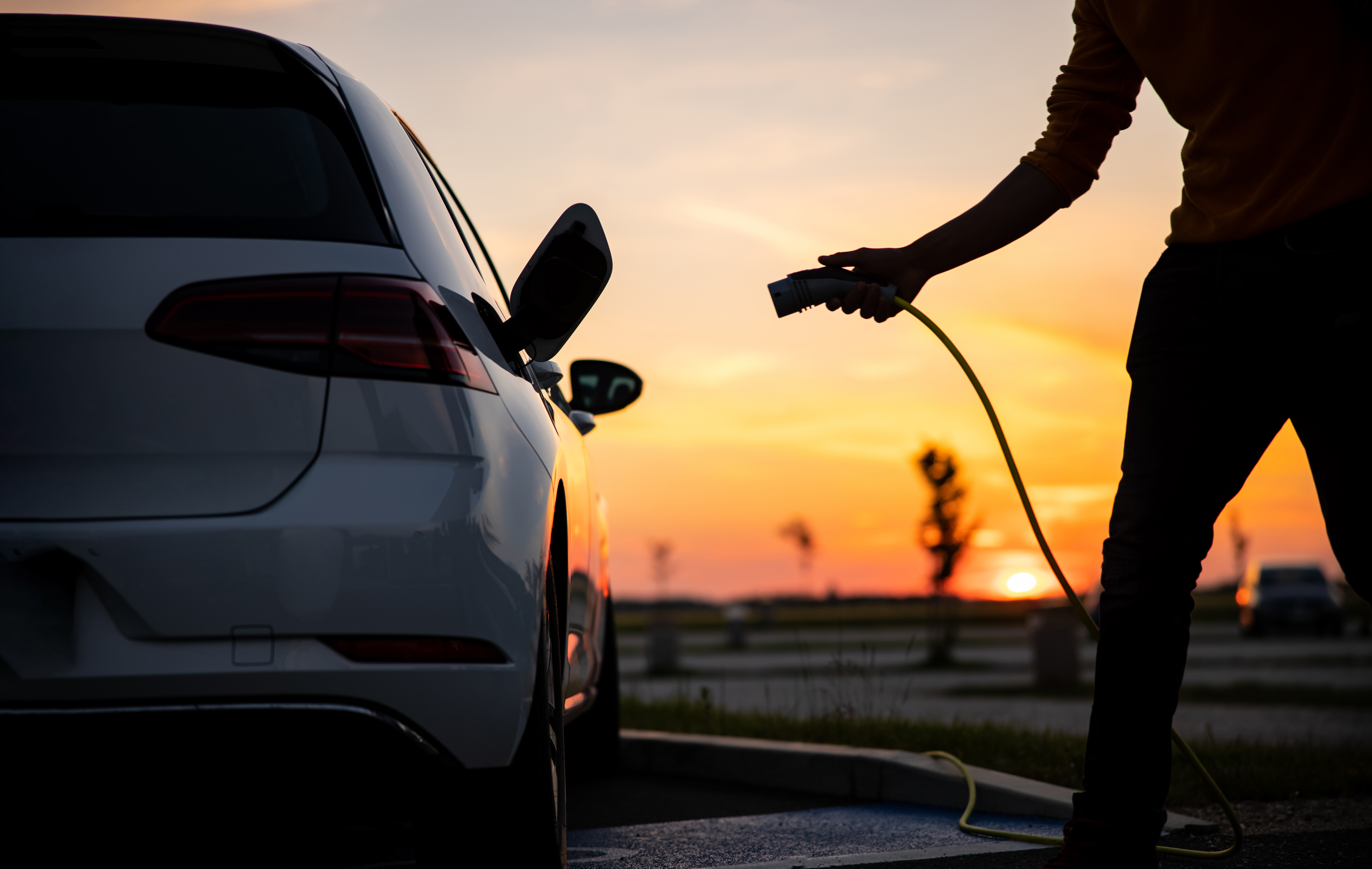 plugging in electric car sunset