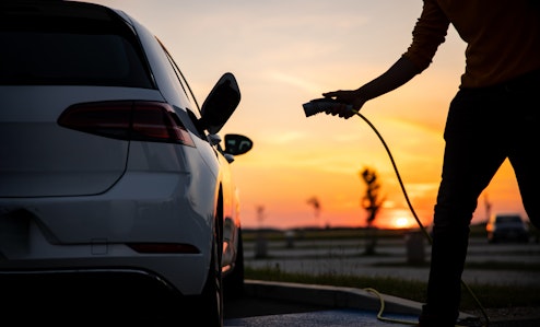 plugging in electric car sunset