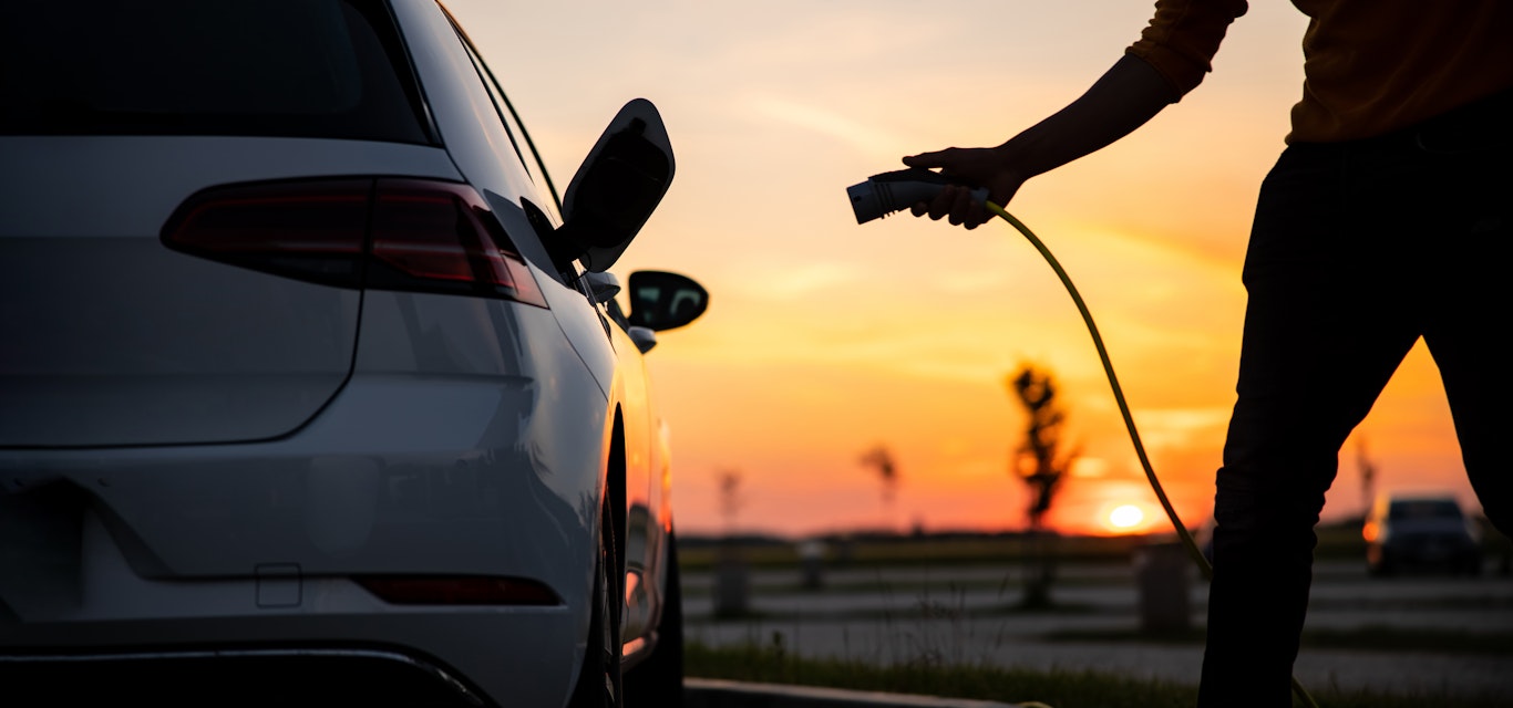 plugging in electric car sunset
