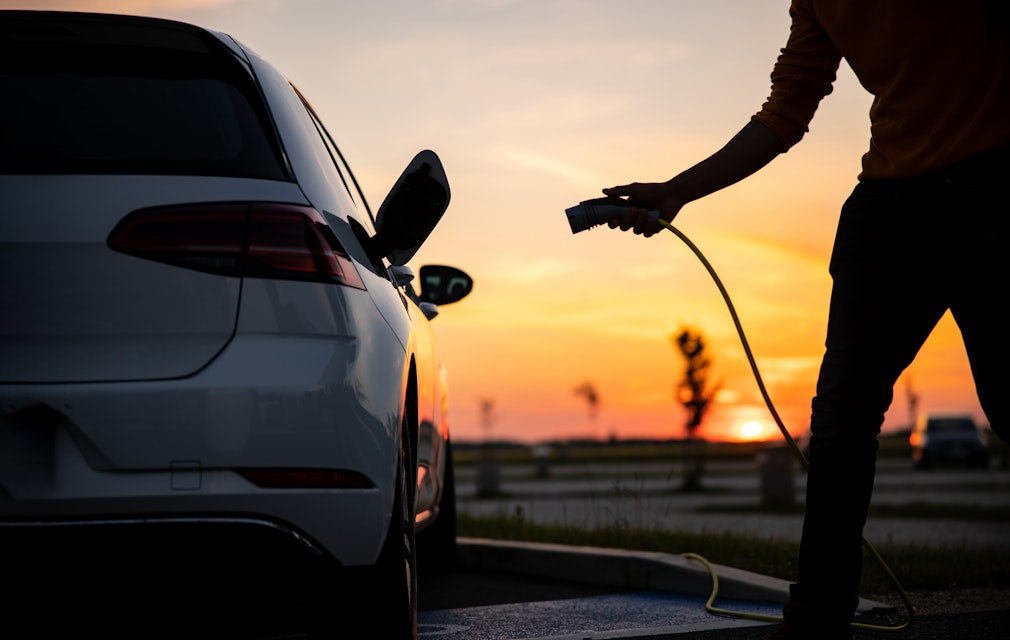 plugging in electric car sunset