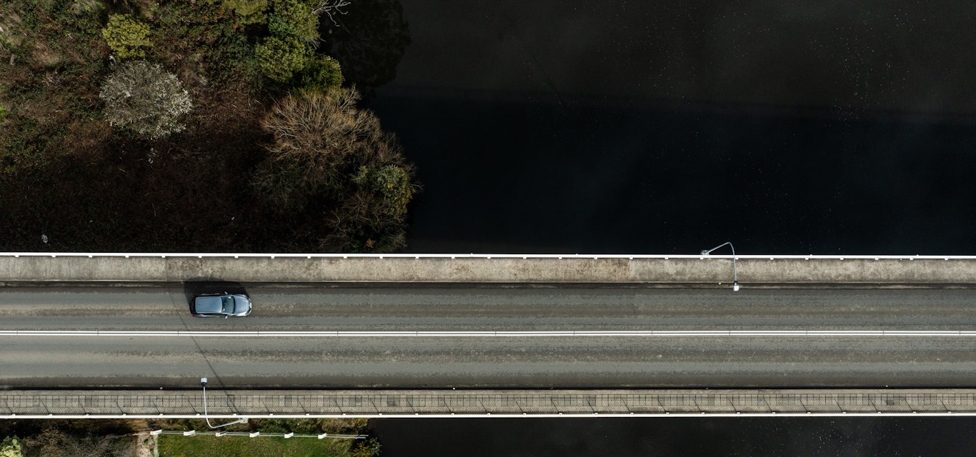 Drone shot of car driving over bridge
