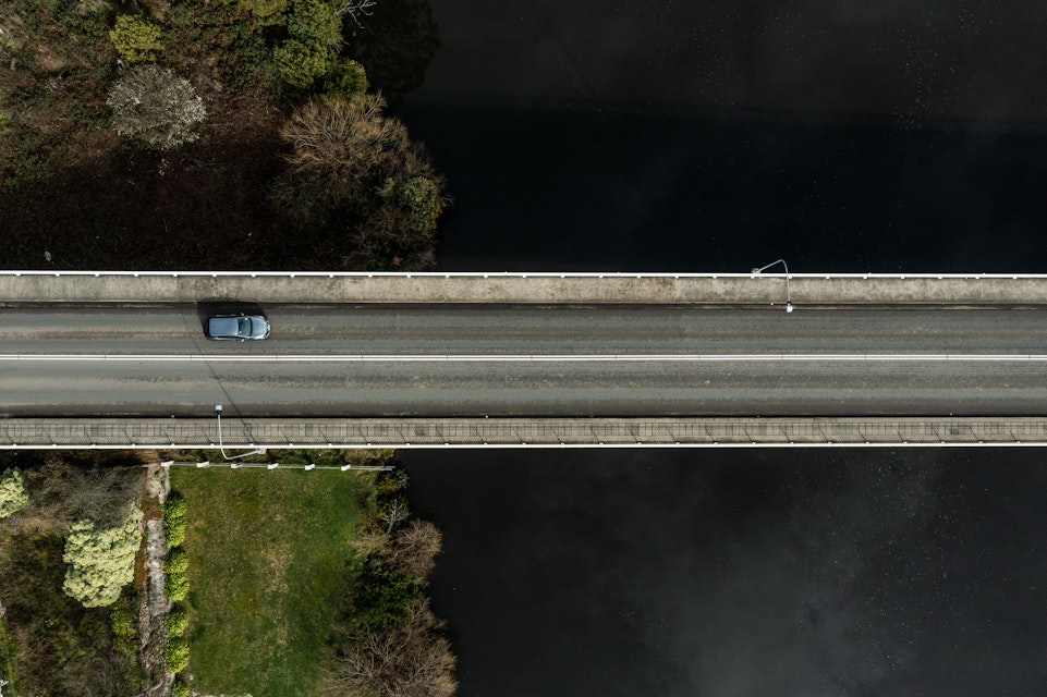 Drone shot of car driving over bridge
