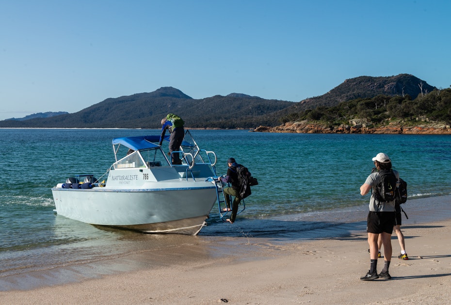 Hikers boarding boat from beach