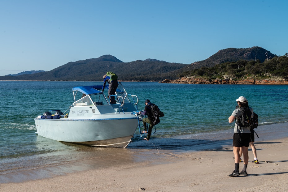 Hikers boarding boat from beach