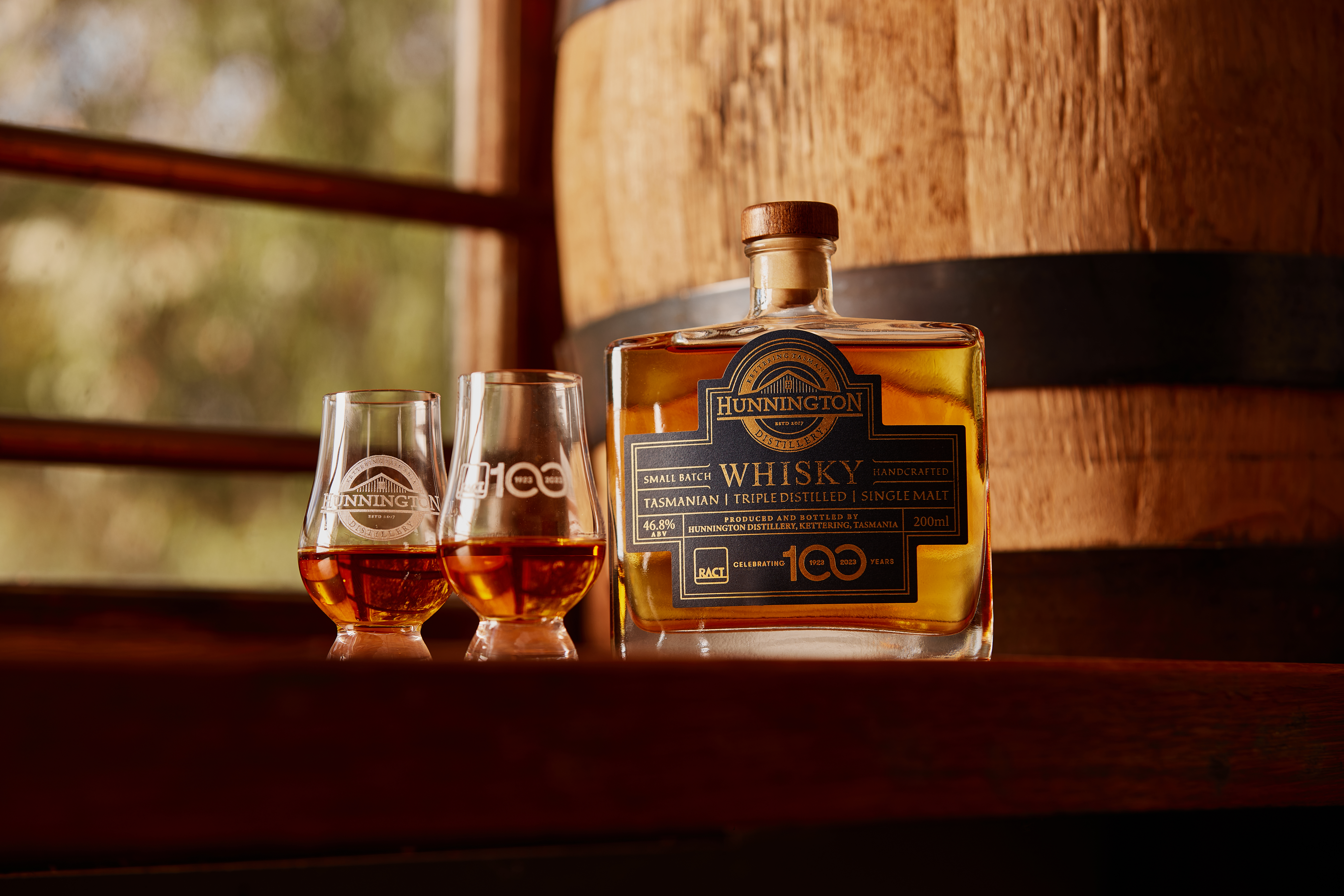 Bottle of whisky with glasses on bench top