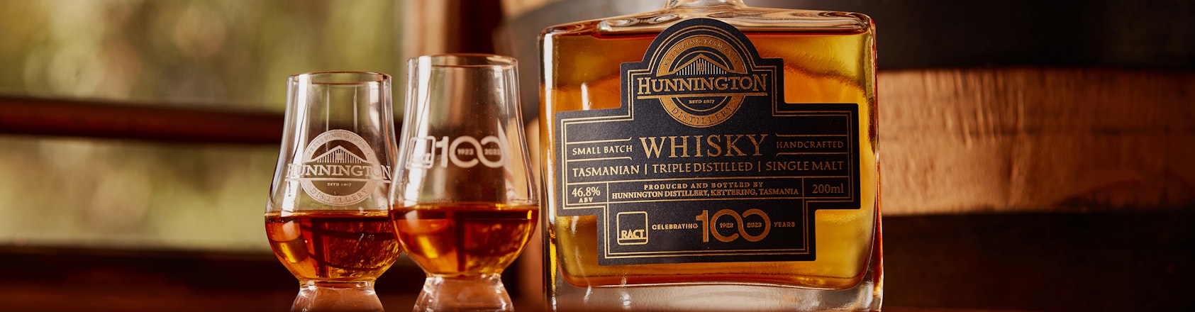 Bottle of whisky with glasses on bench top