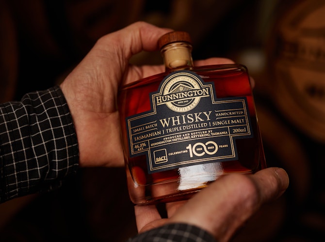 Bottle of whisky in hands of distiller