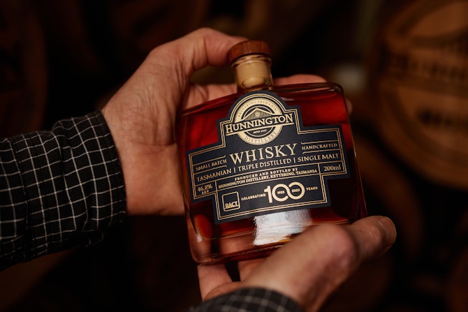 Bottle of whisky in hands of distiller