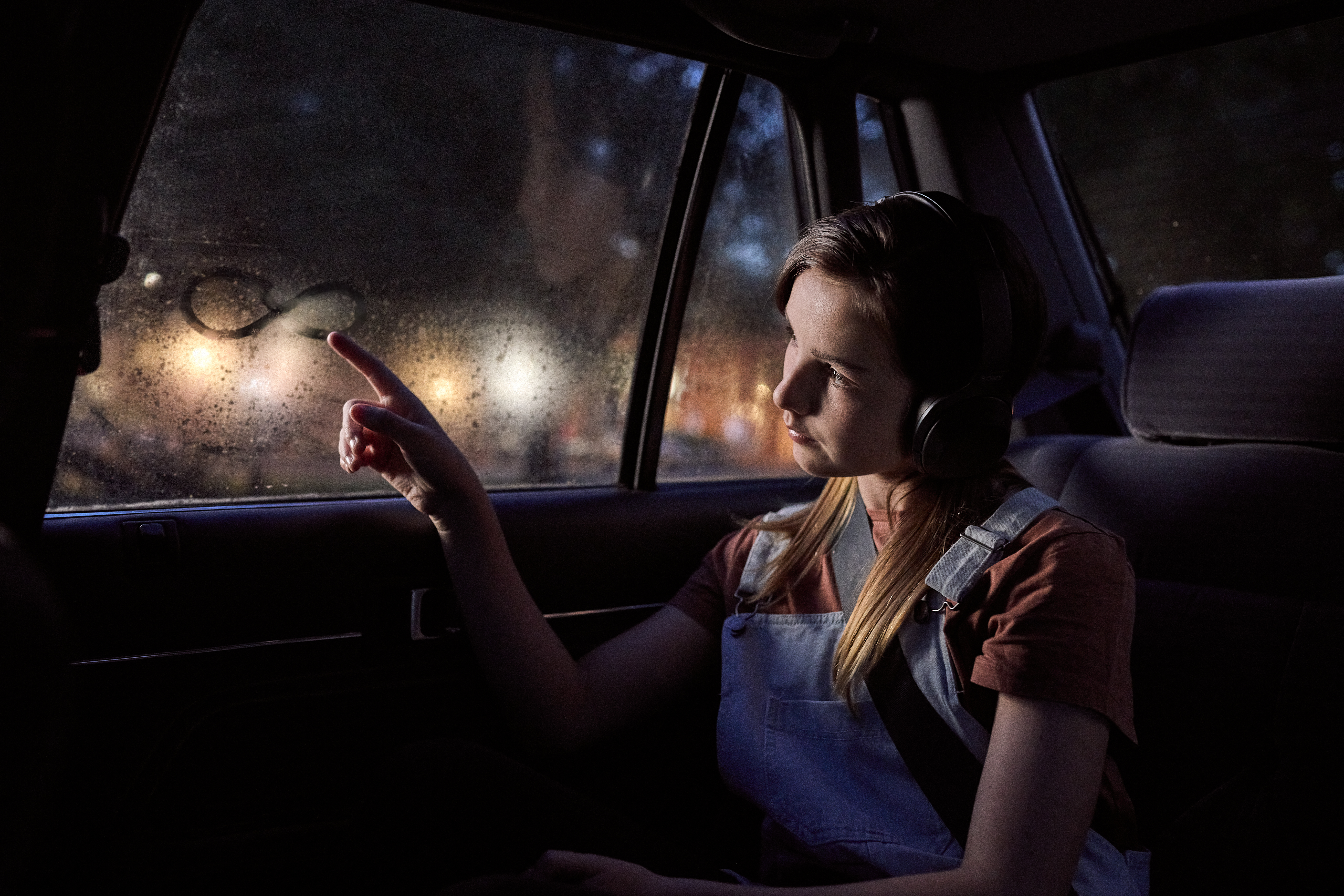 Girl in car drawing infinity logo on window