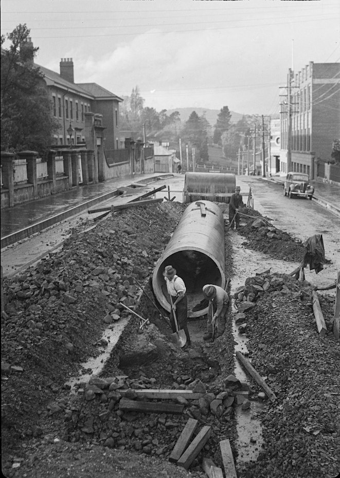 Men digging trenches in middle of road