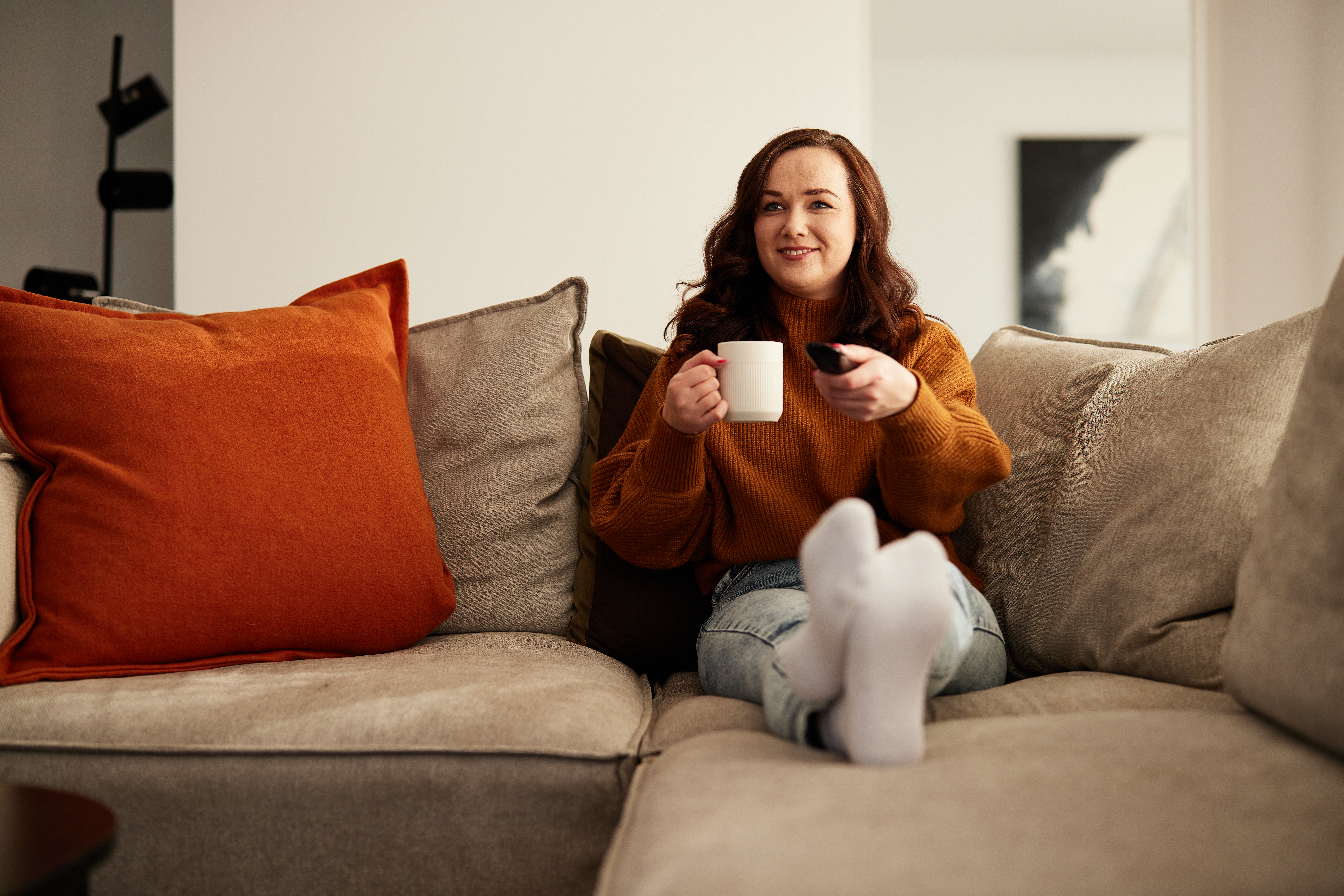 Lady sitting on couch changing tv channels.