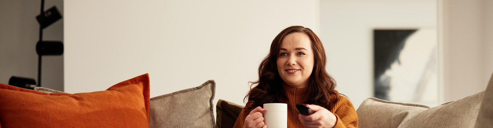Lady sitting on couch changing tv channels.