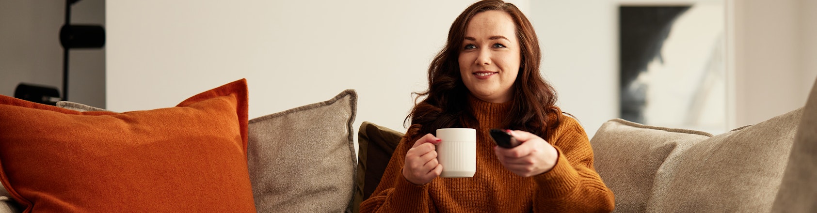 Lady sitting on couch changing tv channels.
