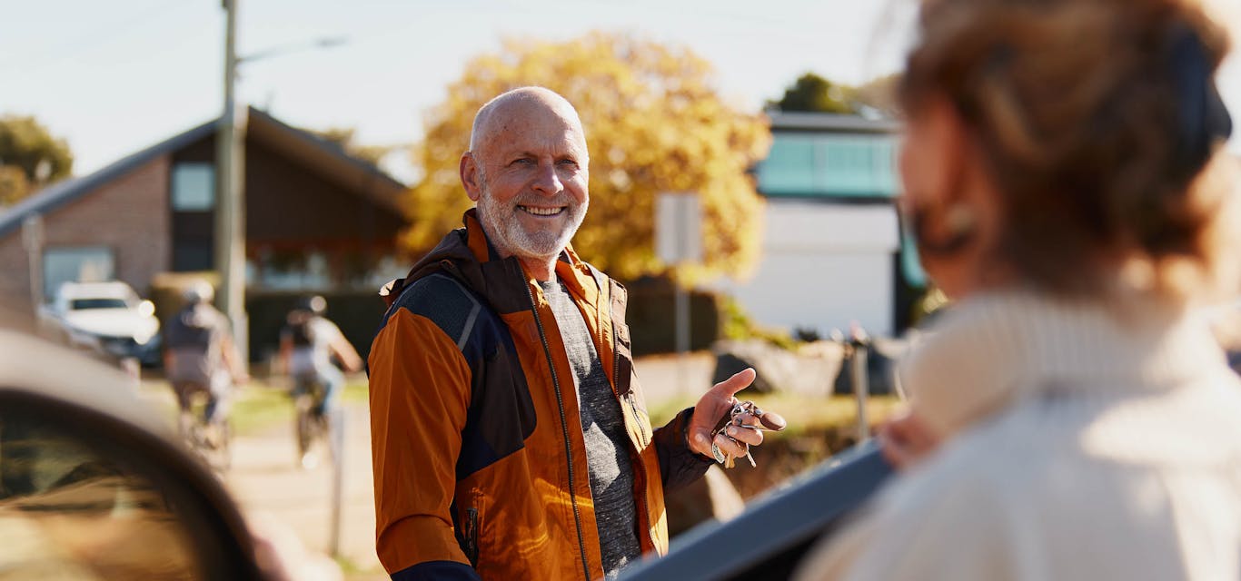 Senior gentleman smiling next to his car with driver door open