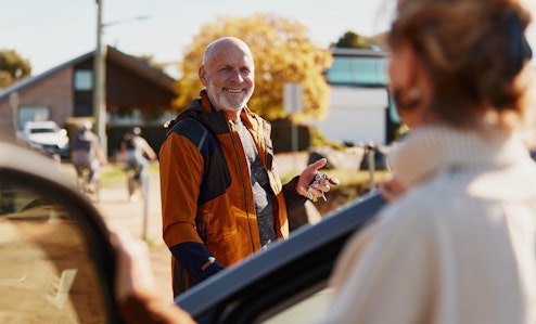 Senior gentleman smiling next to his car with driver door open