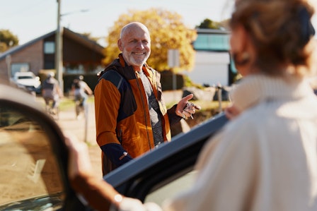 Senior gentleman smiling next to his car with driver door open