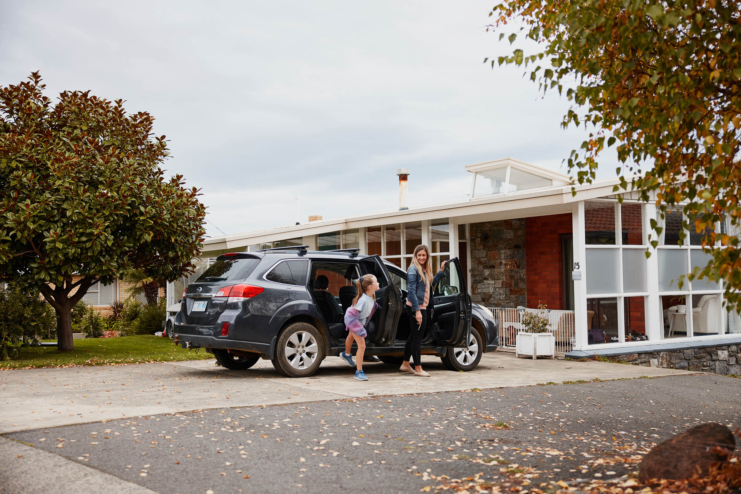 Mum and daughter getting out of the car outside their home